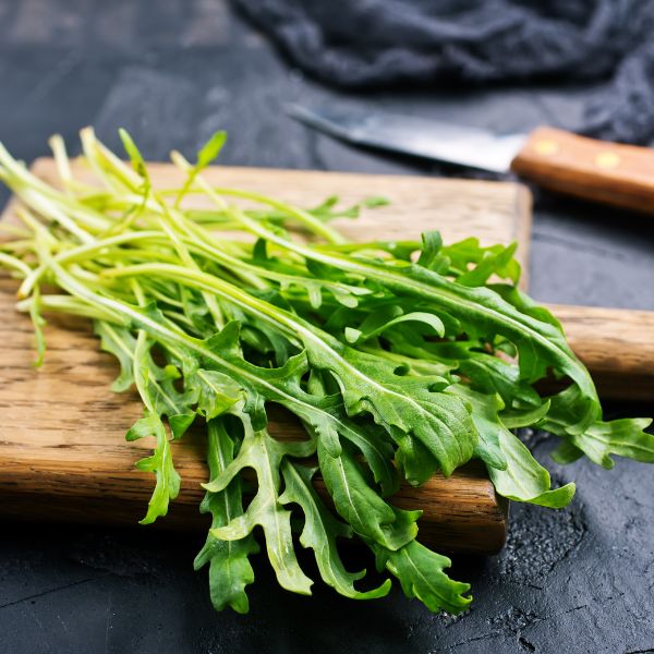Fresh baby arugula vegetable in a Babul 0.125 kg pack, showcasing vibrant green leaves on a clean surface.