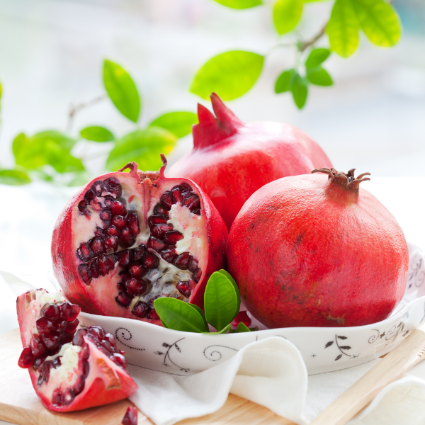 Fresh pomegranates from Sharbatly, 1 kg pack, with vibrant red fruit and leafy stems, ready for healthy snacking or juice.