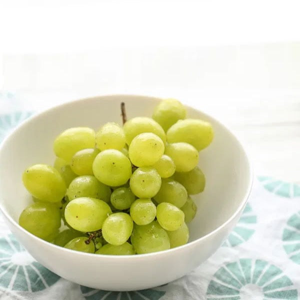 White seedless Cotton Candy grapes in a Sharbatly flower punnet, showcasing plump, ripe grapes with a light green color.